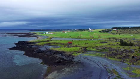 aerial view of rugged coastline with green fields near gardakirkjugardur in gardabaer, iceland