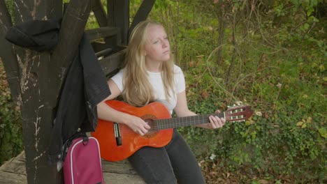 Beautiful-female-songwriter-guitarist-rehearses-forest-wishing-well