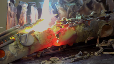 A-blacksmith-uses-gas-welding-to-melt-a-brass-saxophone,-resulting-in-destructive-sparks-and-brightly-coloured-flames