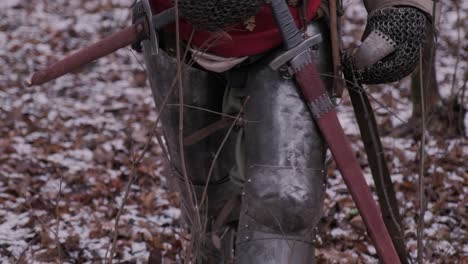 a knight in armor walks through the woods.