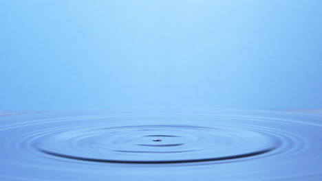 slow-motion shot, two drops of water falling on light blue surface creating a water pillar