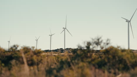 a wide shot of wind turbines working hard to generate renewable energy while preserving the natural beauty of the mountains