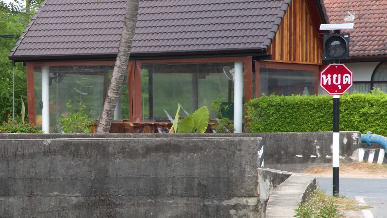 Bidikan jarak menengah statis rambu berhenti Thailand dan lampu merah berkedip di dekat kanal.