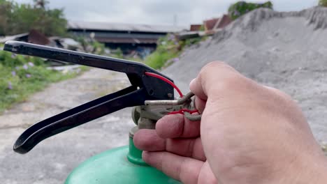 the hand is removing the locking pin on the handle of the fire extinguisher