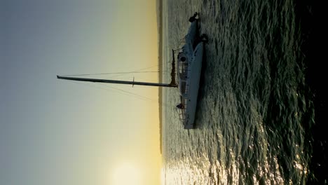 Tiro-Vertical---Yate-De-Catamarán-De-Vela-En-El-Mar-Con-Un-Pintoresco-Amanecer-En-El-Fondo