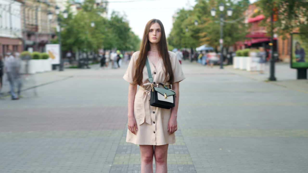 Donna in abito beige su una strada cittadina
