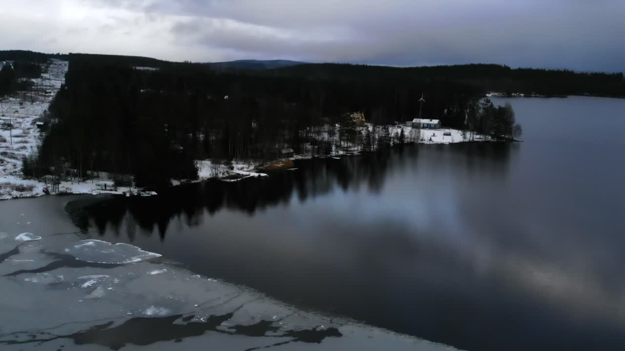 Talven ihmemaa: Tyyni järvi ja mökki lumisessa metsässä