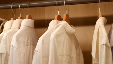 organized closet with white and cream shirts on wooden hangers