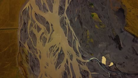 vista aérea superior de un río glaciar que fluye en un valle, con muchas ramas, sobre arena oscura, islandia