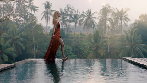 beautiful-woman-walking-by-infinity-pool-wearing-elegant-dress-enjoying-luxury-lifestyle-on-exotic-vacation-at-hotel-spa-with-view-of-tropical-jungle-in-morning-mist