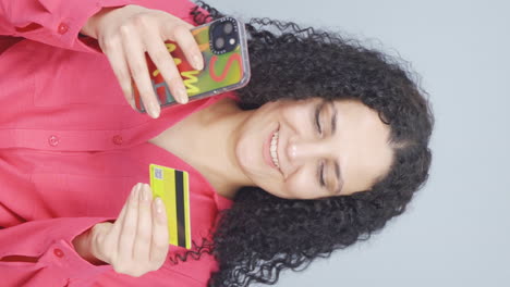 video vertical de una mujer joven comprando con tarjeta de crédito.
