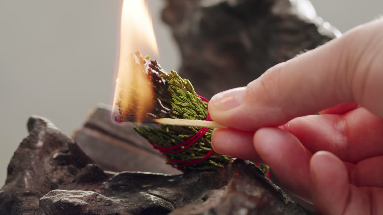 Person holding Palo Santo wood stick in hand, aromatic Palo Santo burning on black background, smoke spreading around, slow motion video clip, high quality 4k close up footage. High quality 4k footage