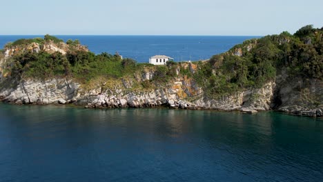 vista aérea cinematográfica de la isla de gramvousa con una iglesia blanca en el medio del marco, rodeada por el mar mediterráneo, pájaros volando, altos picos de montaña, vegetación verde, thassos, grecia