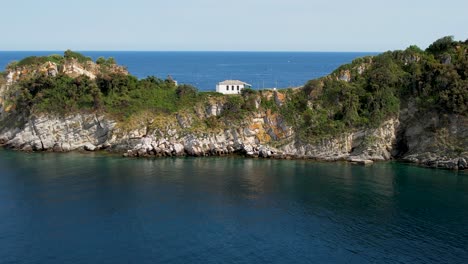 cinematic aerial view of gramvousa island with a white church in the middle of the frame, surrounded by the mediterranean sea, birds flying, high mountain peaks, green vegetation, thassos, greece