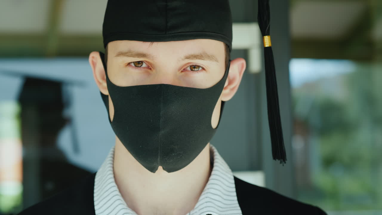 얼굴에 보호 마스크가 달린 가운과 모자를 쓴 졸업생의 초상화