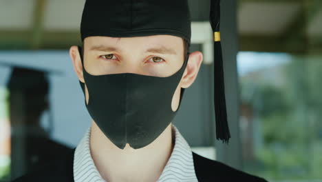 얼굴에 보호 마스크가 달린 가운과 모자를 쓴 졸업생의 초상화