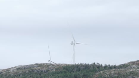 wind turbines on the mountain top spinning against the clouds in the sky