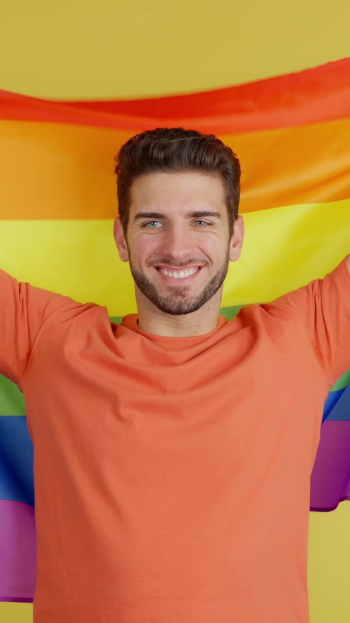 Smiling man holding a rainbow pride flag