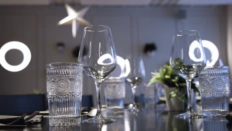 Close-up-shot-of-glasses,-plates,-cutlery-and-napkins-arranged-on-a-table-before-food-been-served-inside-a-restaurant