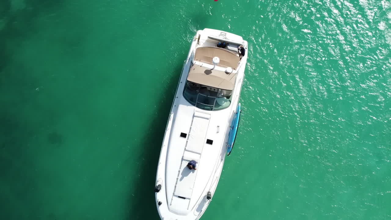 Vista aerea dall'alto di uno yacht bianco con persone su gonfiabili a Puerto Aventuras, Riviera Maya, Messico