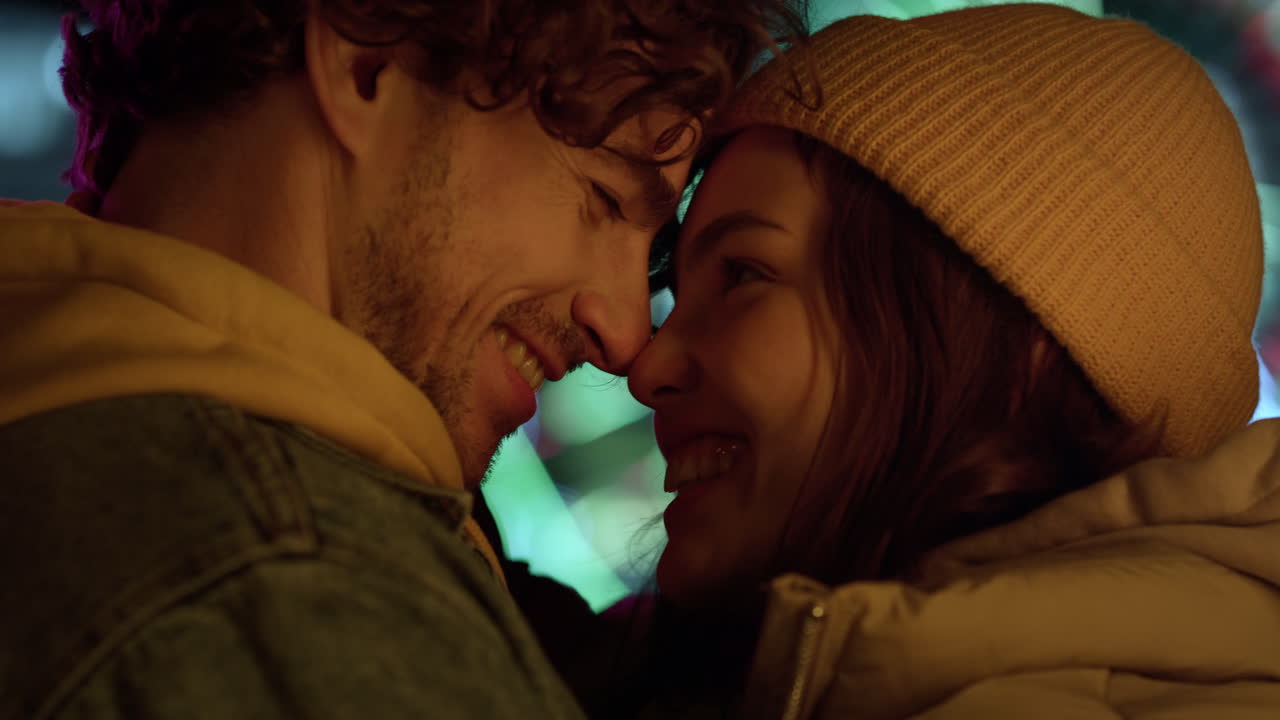 Happy couple touching noses outdoor. Happy man and woman smiling to each other.