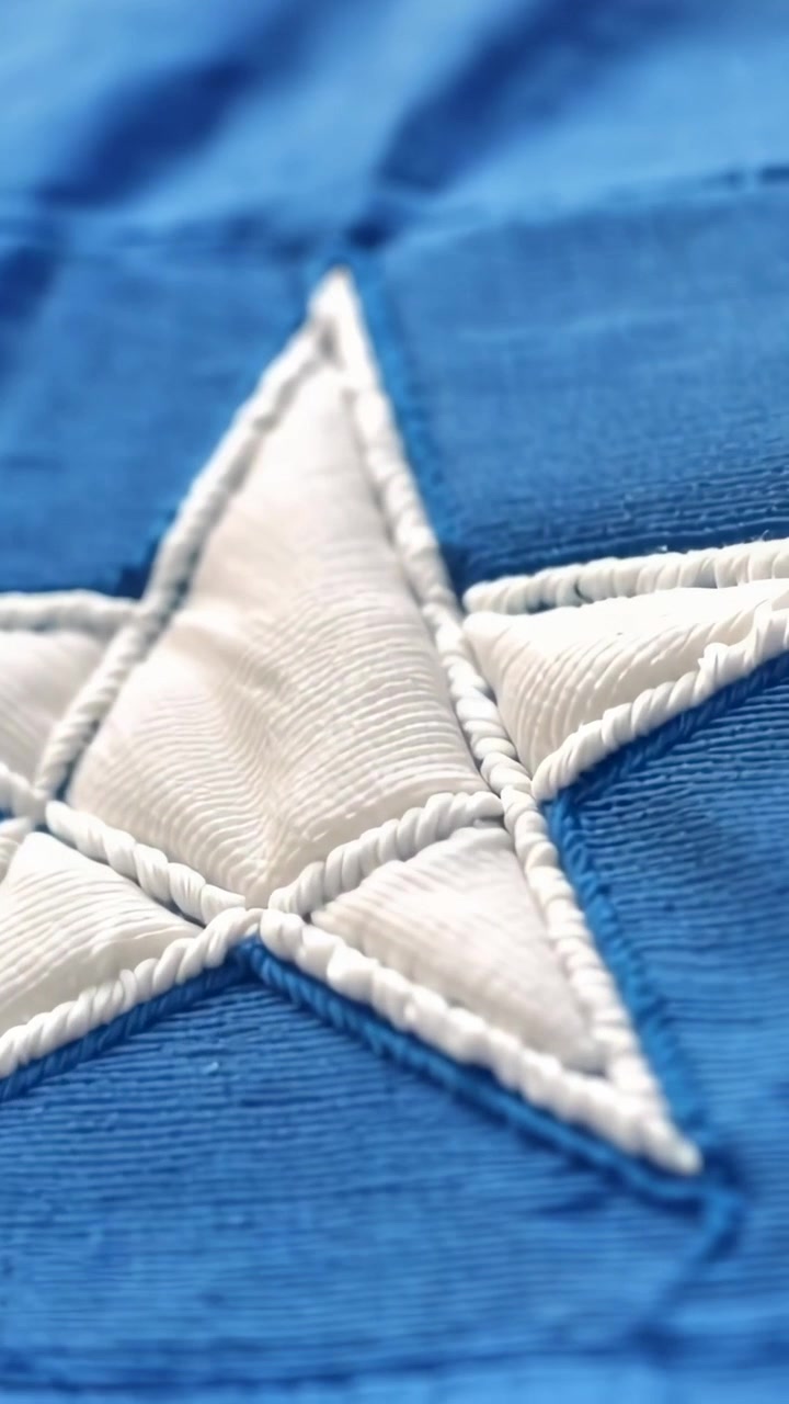 Vertical video: Camera panning down-right, showing white star with rope stitching on blue textile