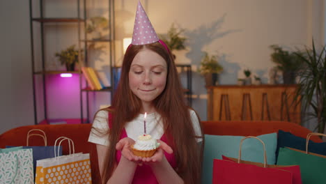 Happy-child-girl-kid-celebrating-birthday-party,-makes-wish-blowing-burning-candle-on-small-cupcake