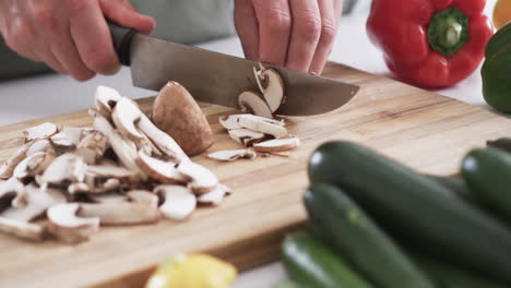 Primer-Plano-De-Las-Manos-Cortando-Champiñones-En-Una-Tabla-Para-Cortar-En-La-Cocina-De-Una-Casa