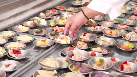 a vibrant display of dim sum dishes being selected by hand in a bustling phuket market