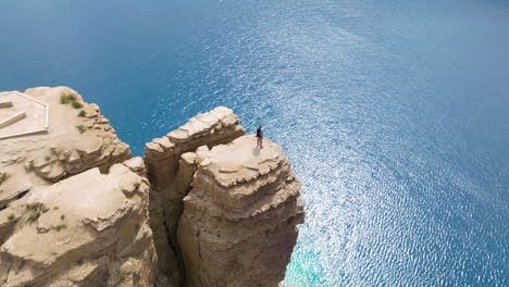 Un-Excursionista-Masculino-Se-Encuentra-En-Lo-Alto-De-Un-Acantilado-Con-Vistas-Panorámicas-Al-Lago-En-El-Parque-Nacional-Band-e-Amir-En-Afganistán