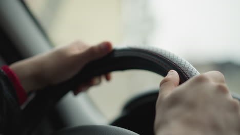 pair of motorist hands on steering wheel controlling vehicle with gentle grip during urban drive, emphasizing smooth motion, focused posture and safe steering with natural light and cabin detail