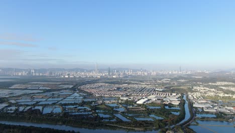 hong kong and shenzhen border line over hong kong rural houses with shenhzen skyline in the horizon, aerial view