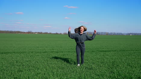 joy girl on a green meadow. beautiful young woman in denim costume enjoys nature in spring. attractive female jumping on a meadow happily.