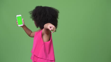 young cute african girl with afro hair showing phone and pointing finger