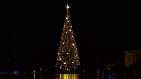 árbol de navidad con luces de colores en el centro de la ciudad y gente disfrutando del ambiente festivo de año nuevo