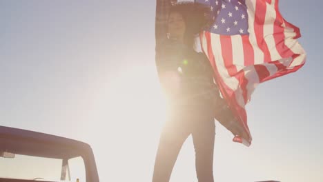 Frau-Steht-Mit-Schwenkender-Amerikanischer-Flagge-Auf-Einem-Pick-up-Truck-4k