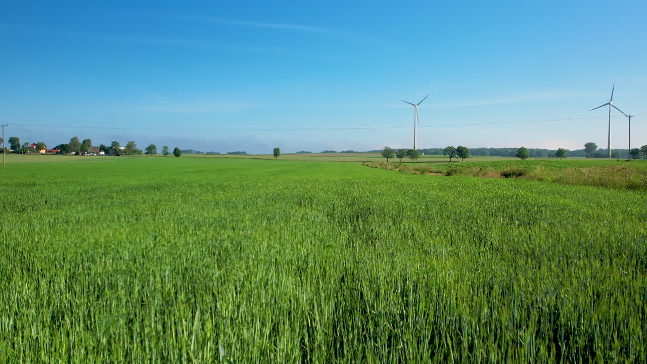 Aerial drone push in towards windmills over farmlands