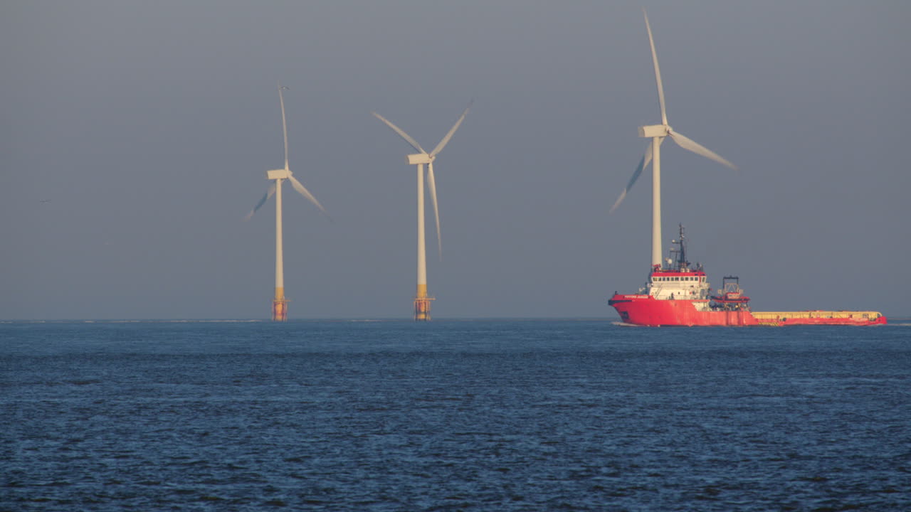 A long shot captures the offshore supply vessel, Putford Jaguar, as it navigates past the offshore wind turbines at Scroby Sands Wind Farm.