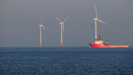 a long shot captures the offshore supply vessel, putford jaguar, as it navigates past the offshore wind turbines at scroby sands wind farm.