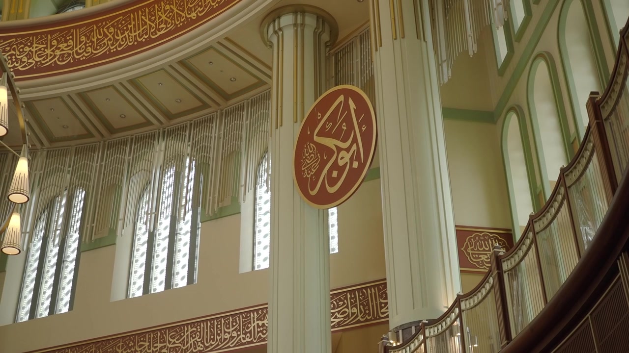 Grand Mosque Interior Featuring Ornate Pillars and Arabic Calligraphy