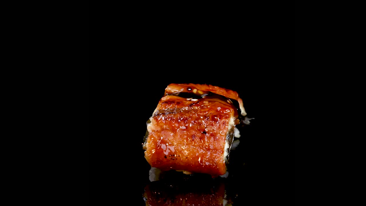 Un Pezzo di Sushi Nigiri Unagi Ruota Fluidamente su una Superficie Nera Riflettente, Illuminato da Luci da Studio che Evidenziano Consistenza e Dettagli per Tutto il Video di 15 Secondi