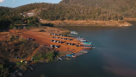 traditional colored thai boats moored on a brown beach near packed cars in srilanna national park