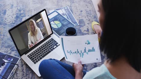 African-american-woman-holding-a-document-having-a-video-call-on-laptop-at-home