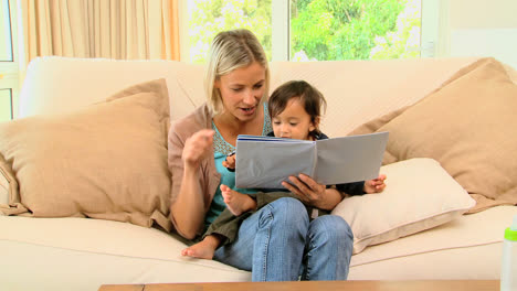 Madre-Joven-Y-Bebé-Mirando-Un-Libro-Ilustrado.-