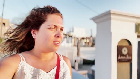 woman taking santorini street selfie in warm sunshine