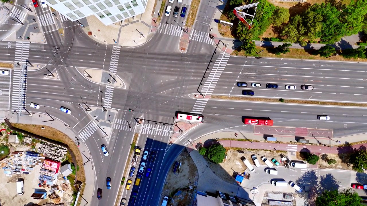 City street junction with red bus, Bratislava, Slovakia. High angle perspective of urban traffic moving across pedestrian lines near building structures.