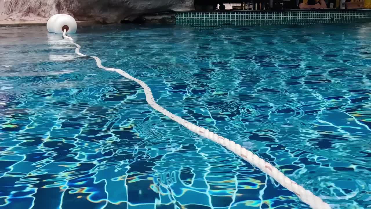 A serene view of a pool with a floating rope and buoy, capturing the tranquil water surface.