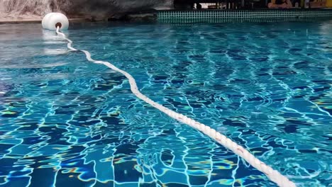 a serene view of a pool with a floating rope and buoy, capturing the tranquil water surface.