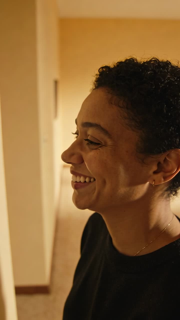Vertical video: Smiling right woman laughing on off cam cue in hall in dark top chain, copy space