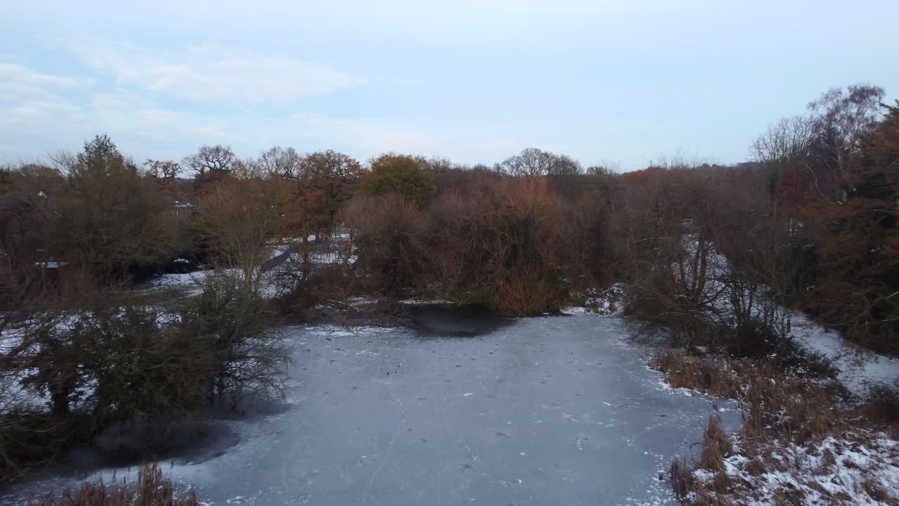 Drone flying over frozen pond with snow and ice in cold winter weather